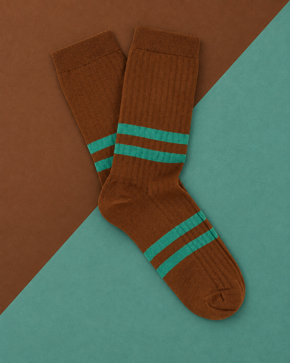 Escuyer striped socks in Brown with green stripes, laid flat on a two-tone brown and teal background