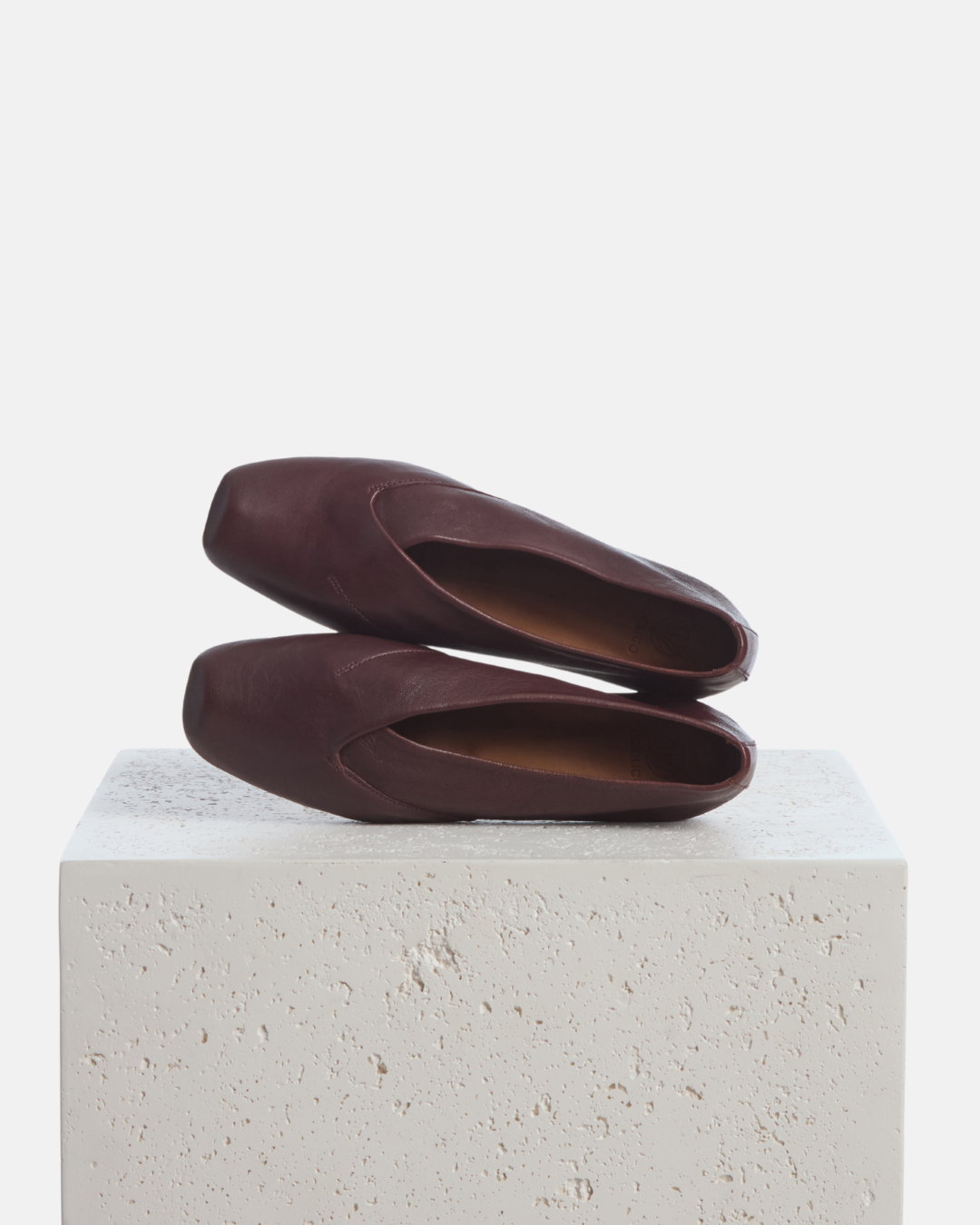 Coclico Franklin Flat in Pecan leather, brown pointed toe flats styled on a stone plinth