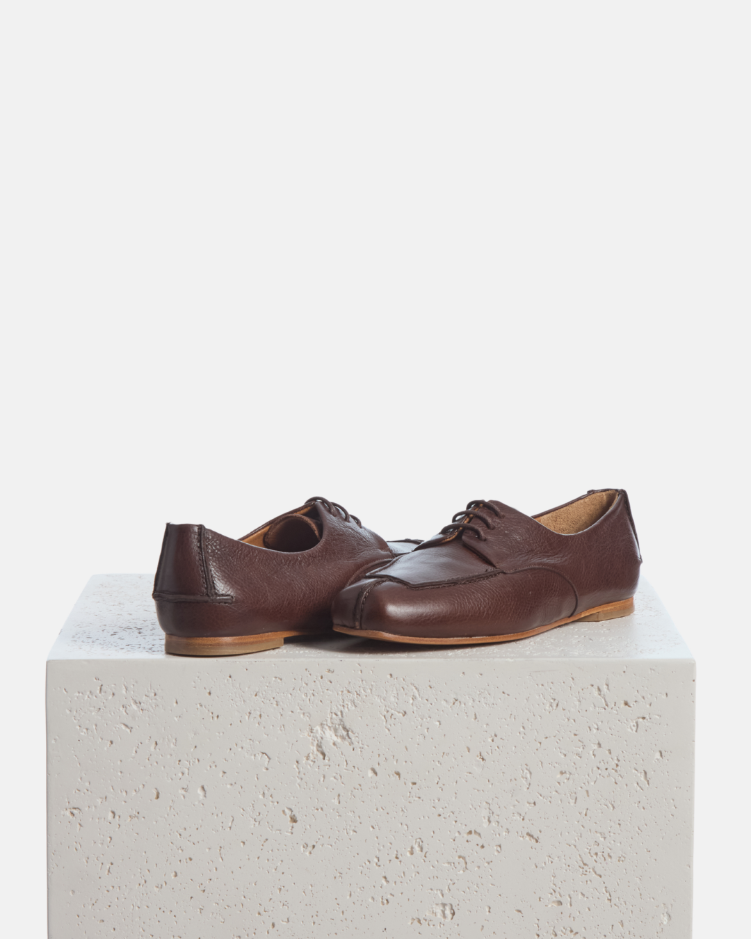 Coclico Fubee Oxford in Castagno, chestnut leather lace up oxfords styled on a stone plinth