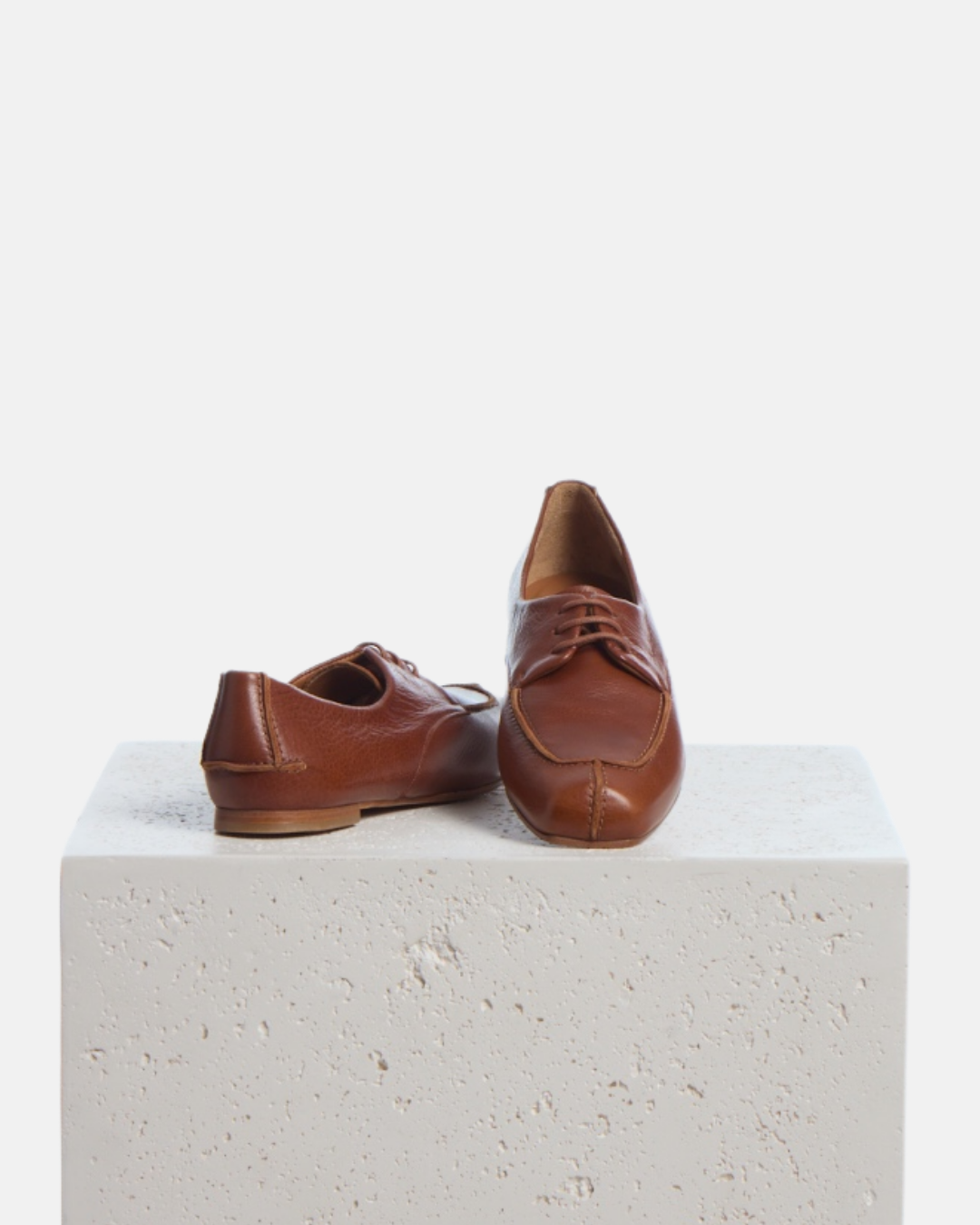 Coclico Fubee Oxford in Cuero, tan leather lace up oxfords styled on a stone plinth