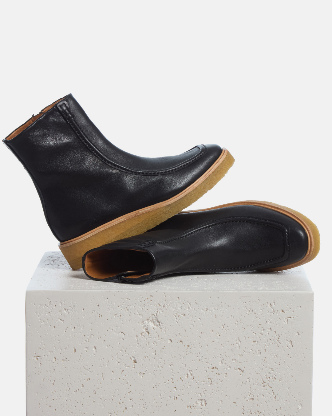 Coclico Haber Boot in black leather, moc toe boots with natural crepe wedge soles styled on a stone plinth