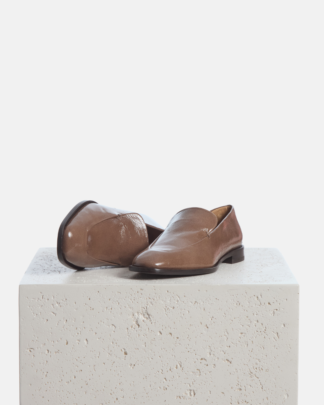 Coclico Halyn Loafer in Boue crinkled patent, square toe loafers styled on a stone plinth