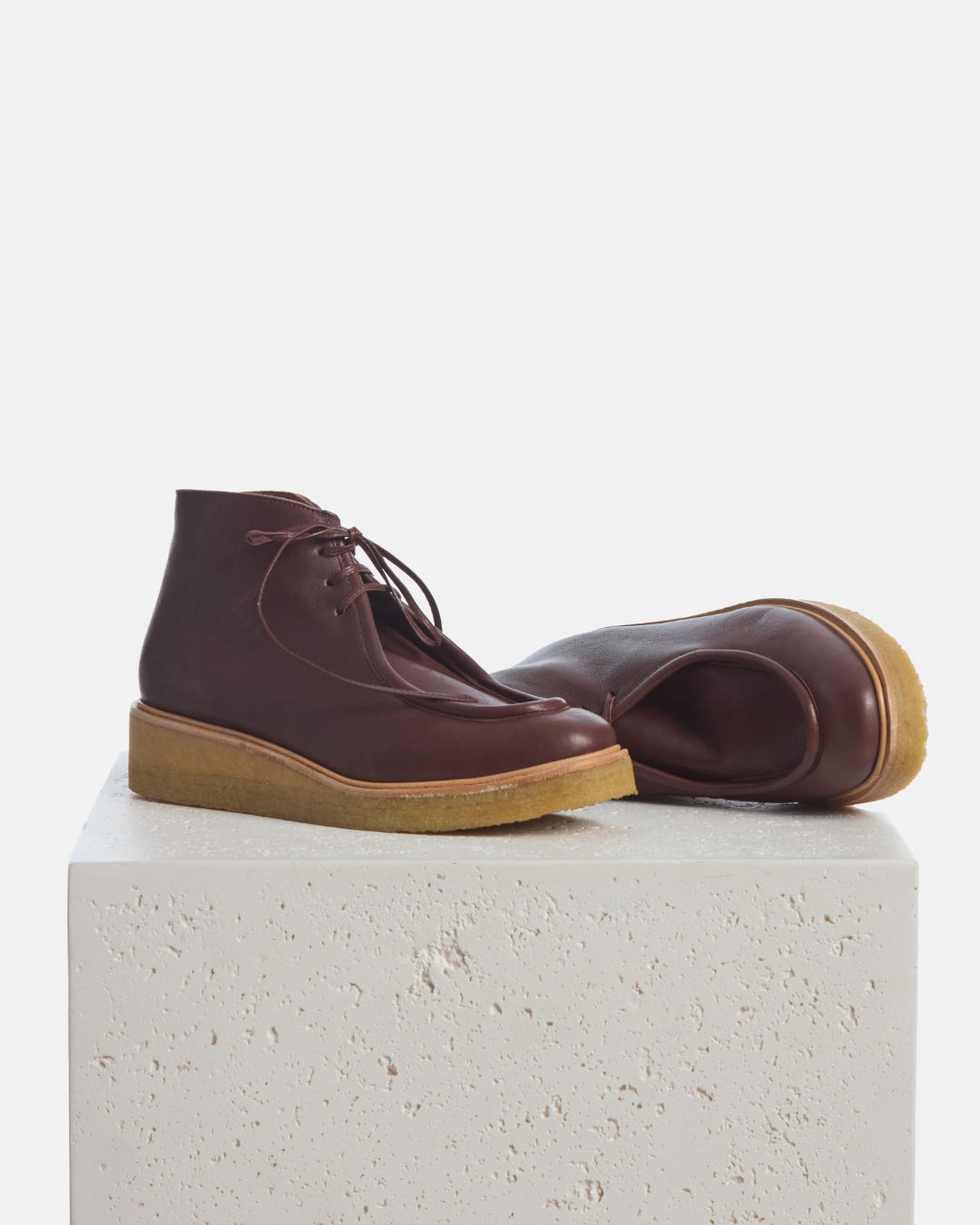 Coclico Hester Boot in Pecan leather, lace up crepe sole ankle boots styled on a stone plinth