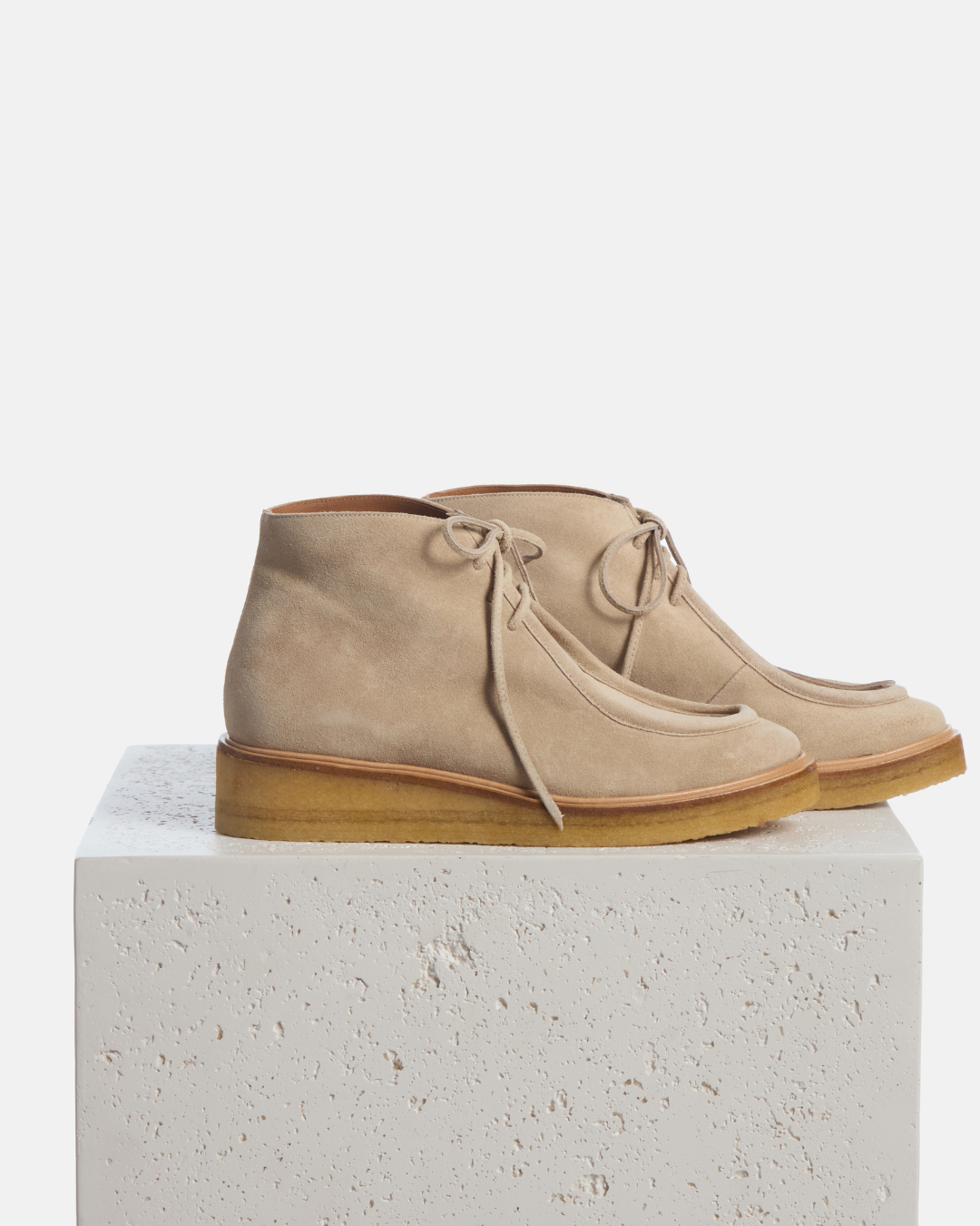 Coclico Hester Boot in Sand suede, lace up ankle boots with crepe soles styled on a stone plinth