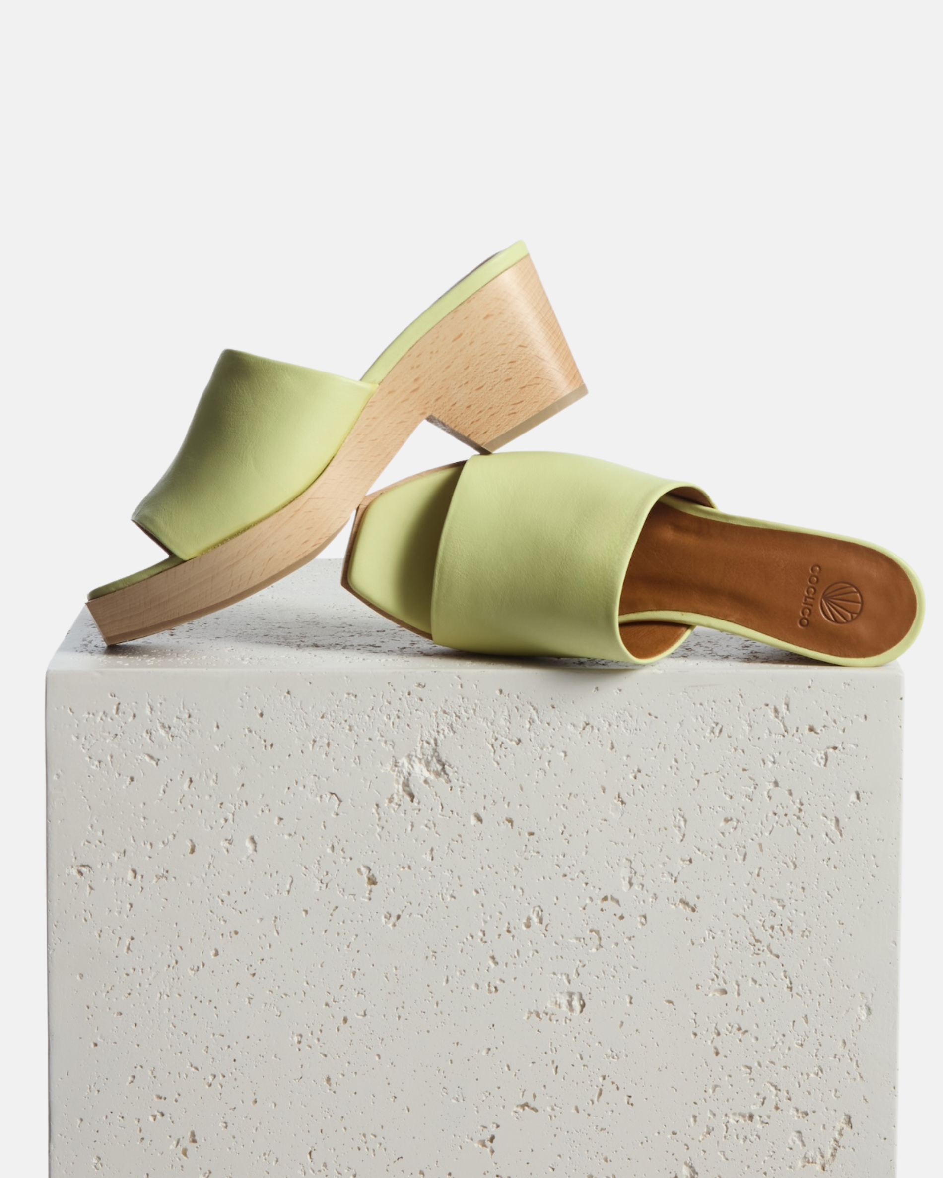Clogs on a plinth: lemon yellow leather slide clog sandal with a wide upper, squared toe, and solid ash wood sole