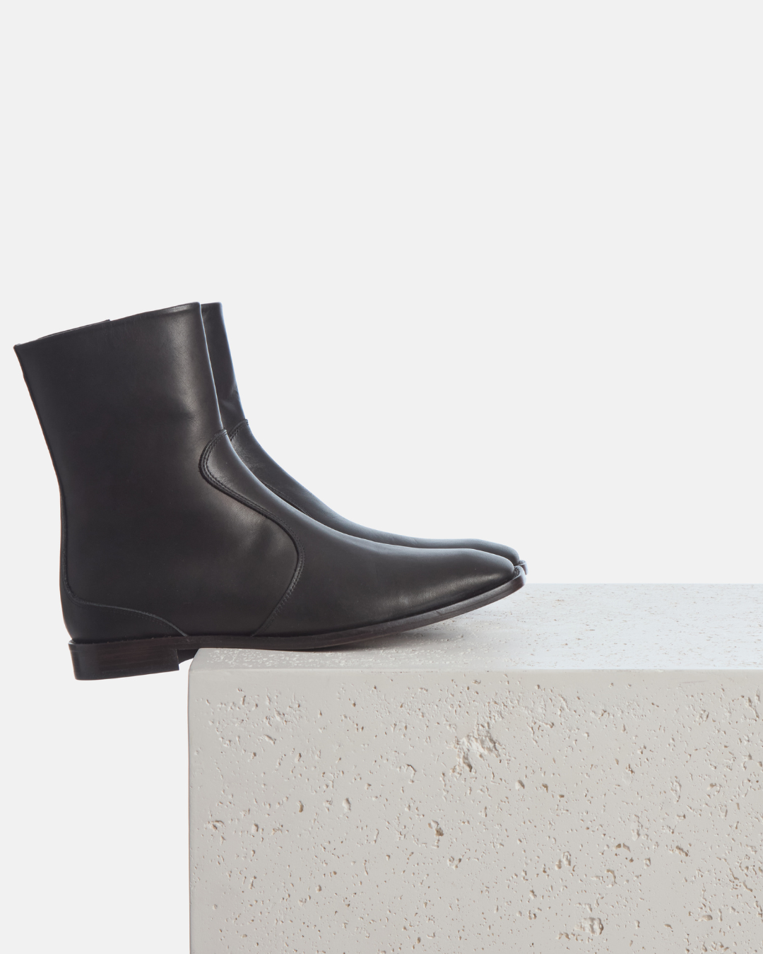 Coclico Hopper Boot in black leather, flat square toe ankle boots styled on a stone plinth