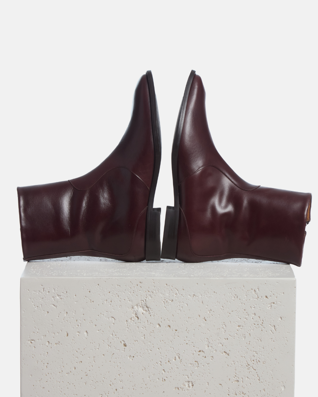 Coclico Hopper Boot in Oxblood leather, flat square toe ankle boots styled on a stone plinth