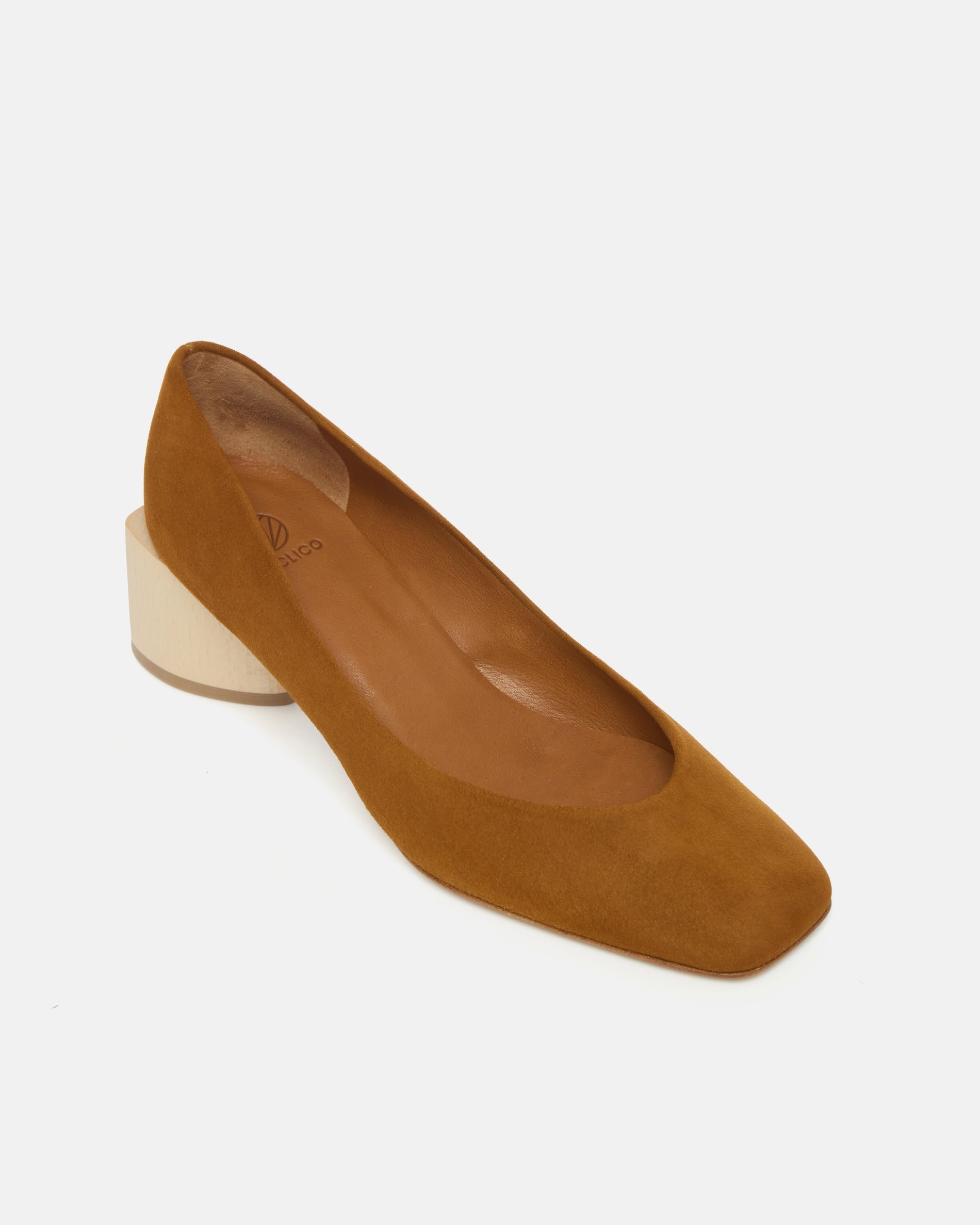 Angled view of a brown suede pump with a square toe and a solid architectural wood block heel on a white background
