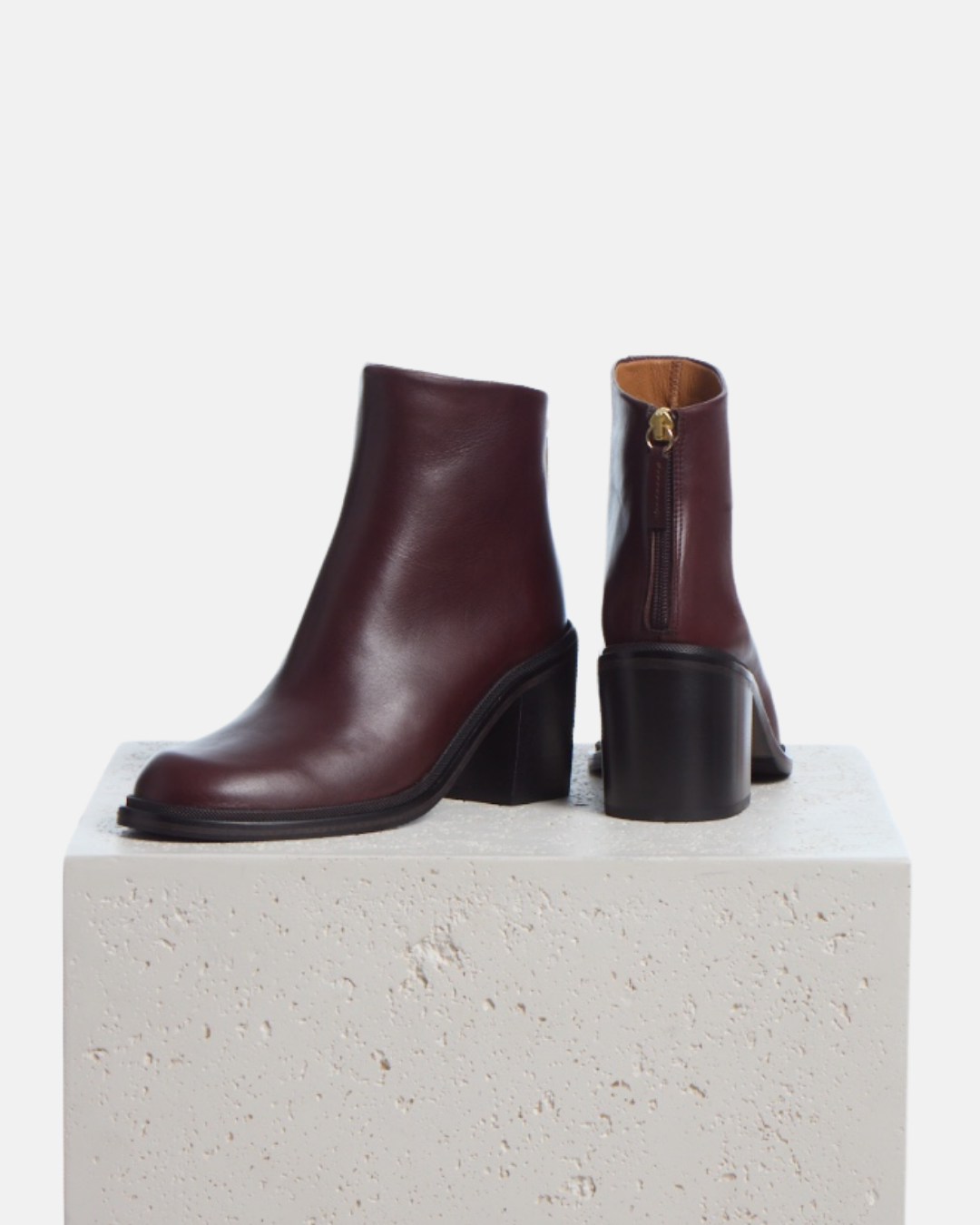 Coclico Lola Boot in Oxblood leather, block heel ankle boots styled on a stone plinth