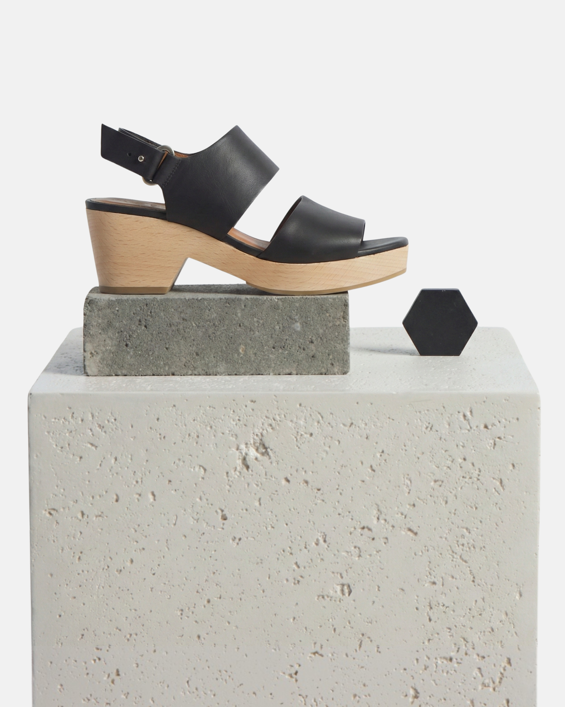 Black leather clog sandals with a chunky wooden heel, featuring a peep-toe design and an adjustable ankle strap with a silver buckle.