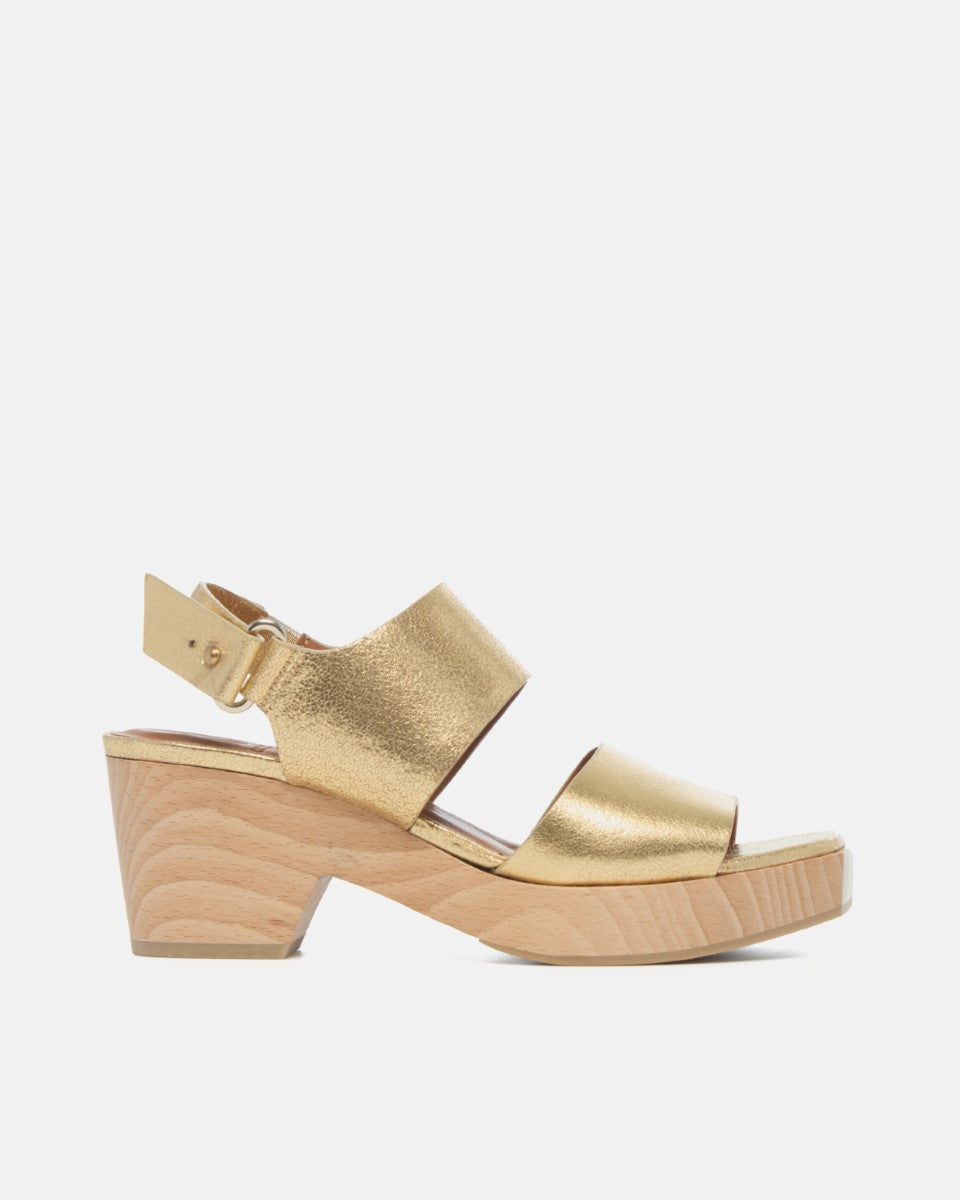 Side view of gold leather clog sandal with wide straps, adjustable slingback, squared toe, and solid ash wood block heel on a white background.