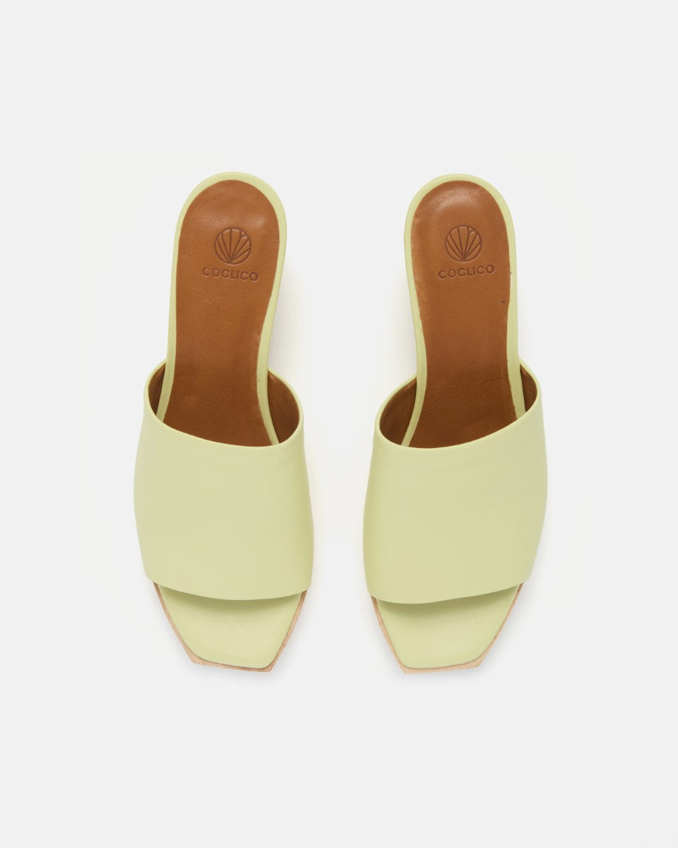 Front  view of a lemon yellow leather slide clog sandal with a wide upper, squared toe, and solid ash wood sole on a white background.