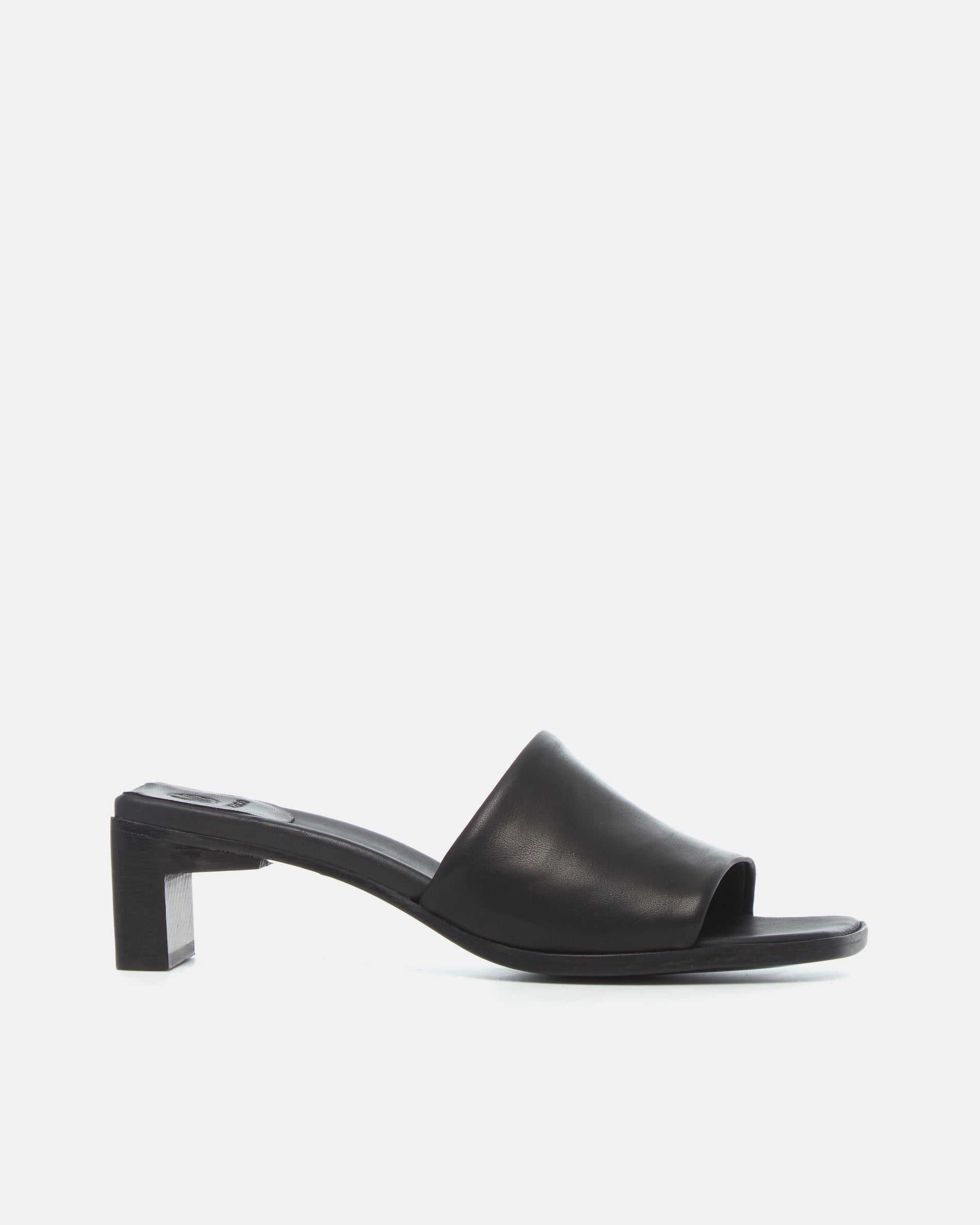 Side view of a black leather sandal with a wide band, squared toe, and sculptural wooden block heel