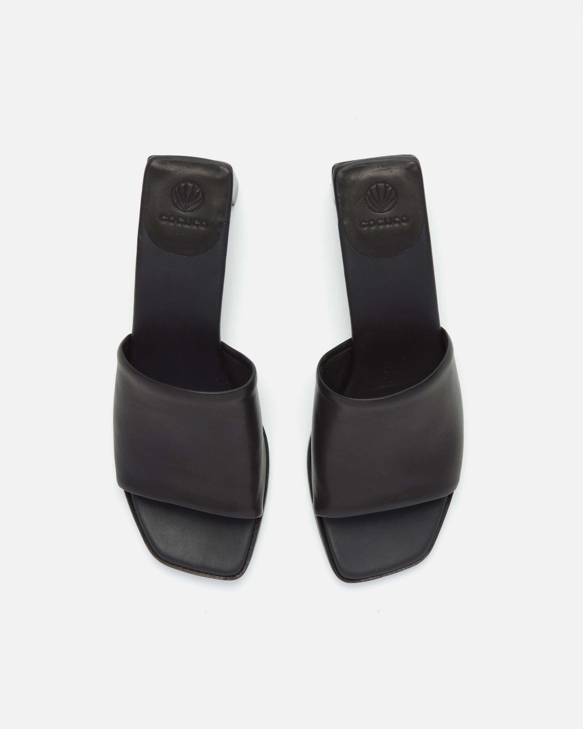 Top view of a black leather sandal with a wide band, squared toe, and sculptural wooden block heel