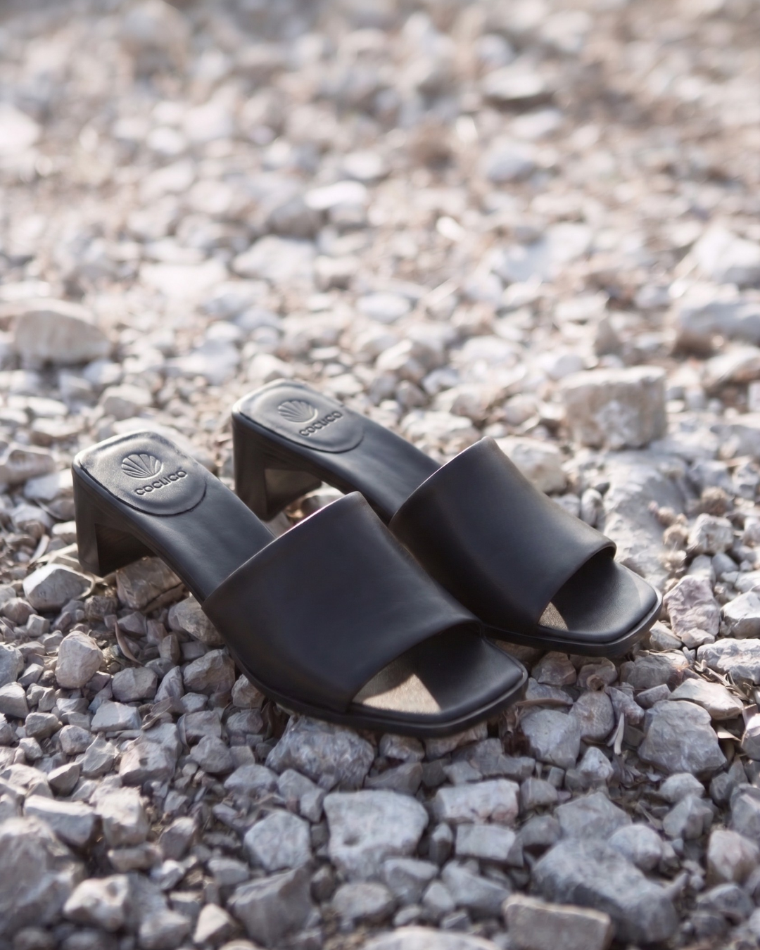 Black leather mid-heeled slide sandals on stones