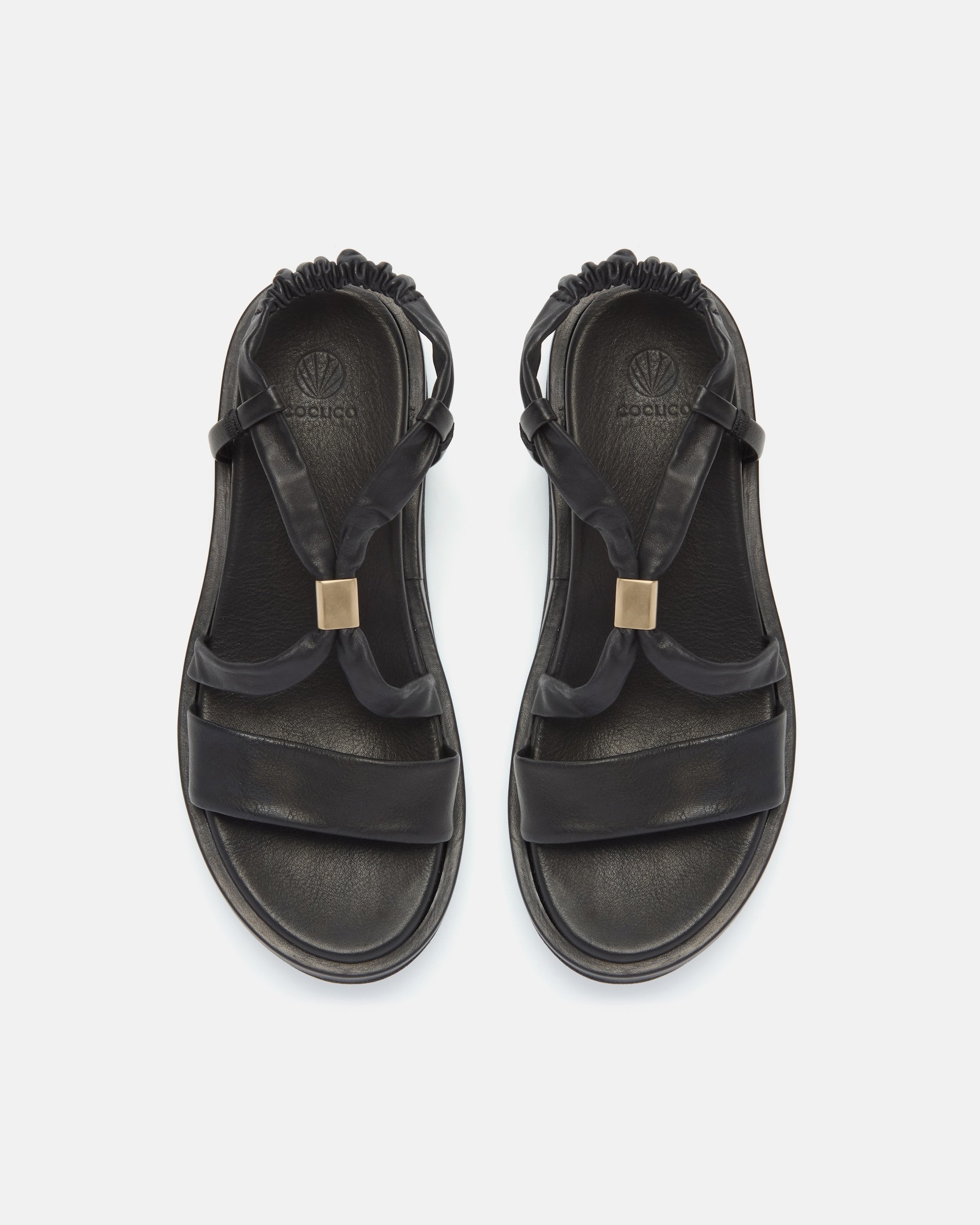 Top view of a black leather slingback sandal with soft tubular straps, brushed-metal keeper detail, and a cushioned platform sole on a white background