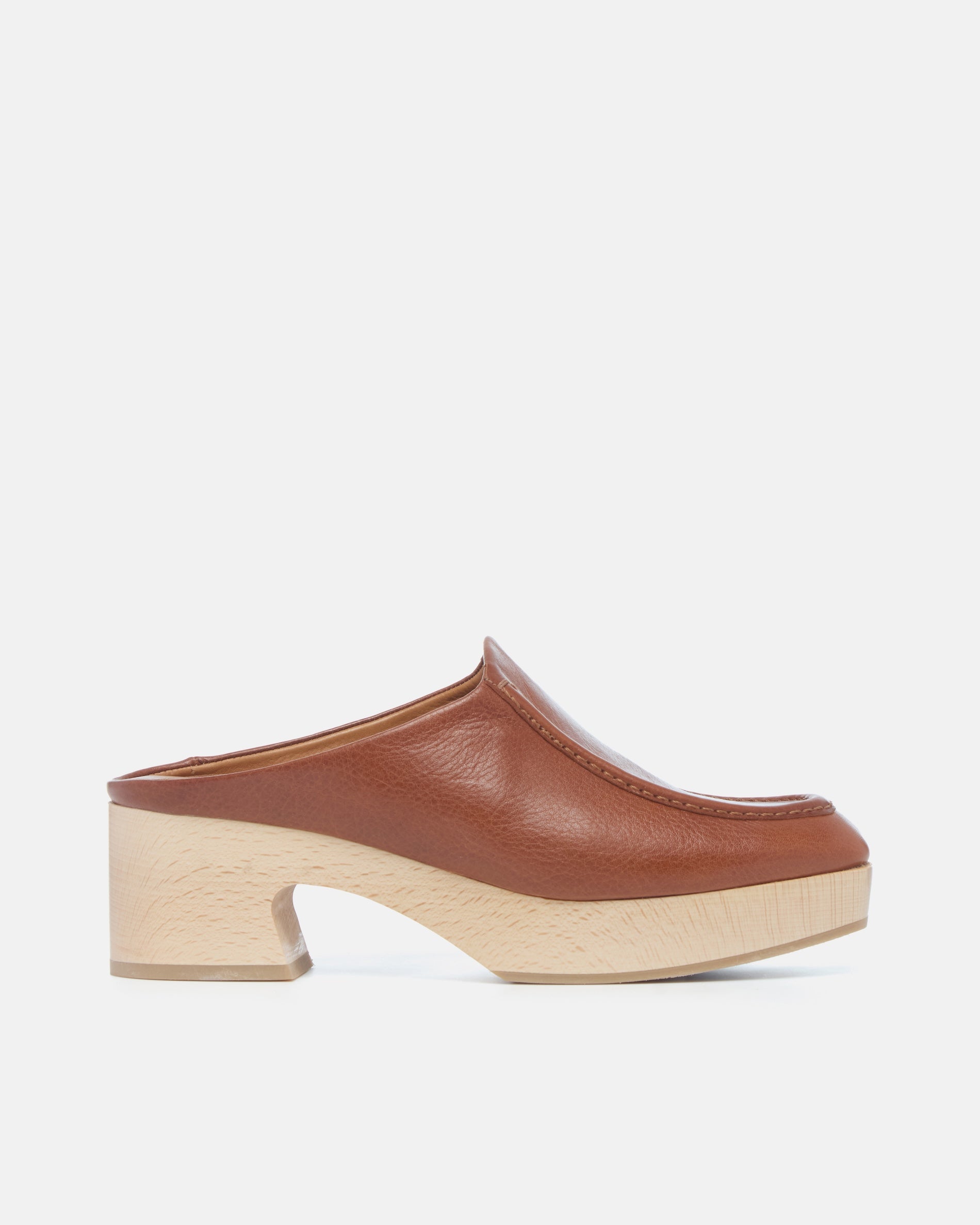 Coclico Qadira Clog in Cuero leather, side view of a tan clog mule on a natural wood platform