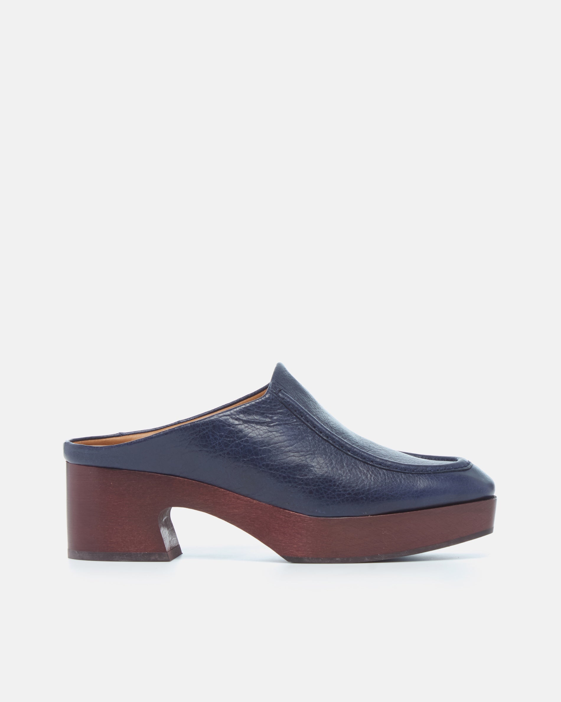 Coclico Qadira Clog in Marino, side view of a navy leather clog mule on a mahogany platform