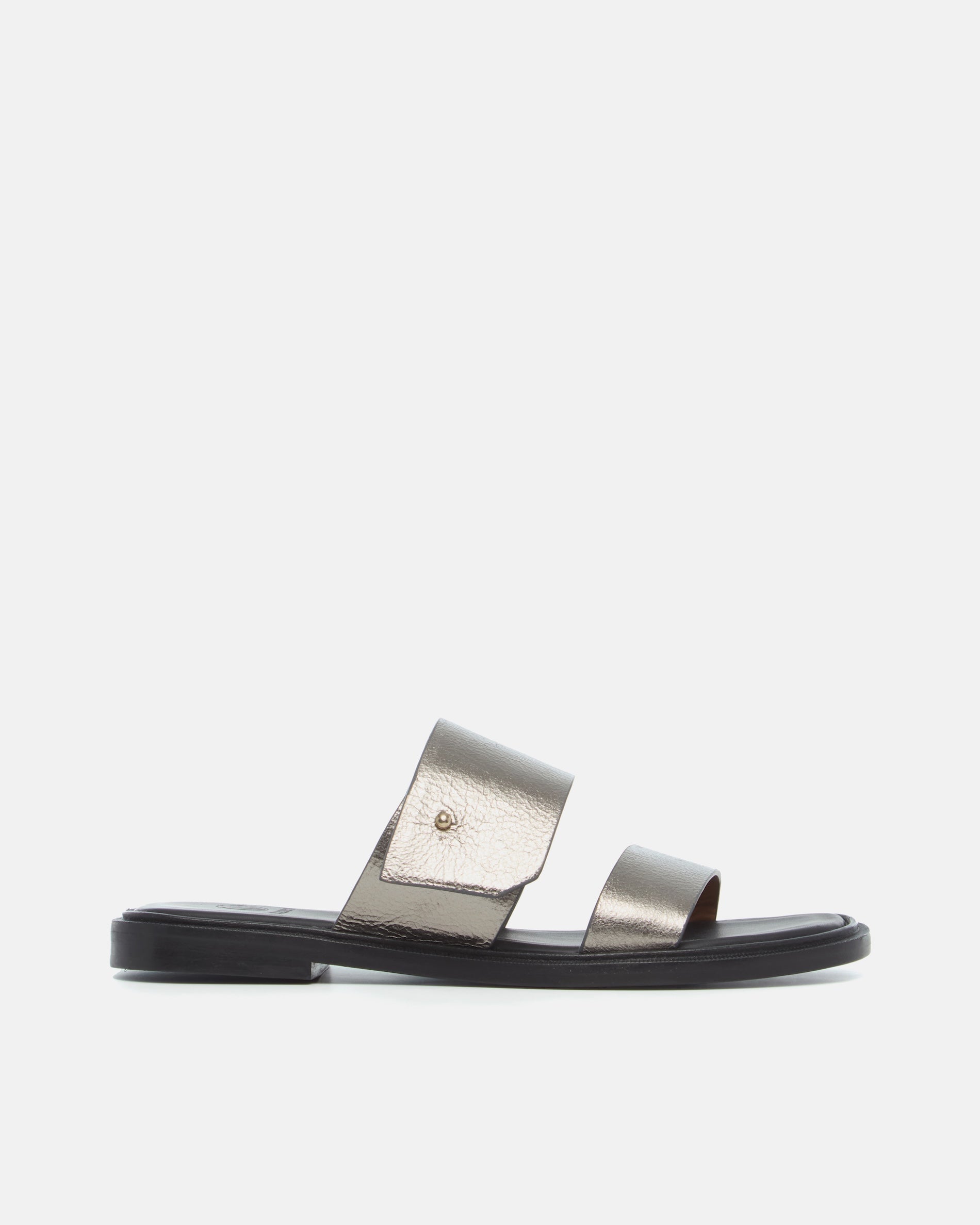 Side view of a pewter metallic leather slide sandal with two wide straps, a subtle metal peg detail, cushioned leather footbed, and flat leather sole