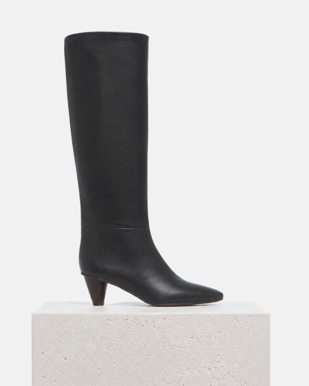 Pair of Coclico Sirleaf Boots in black leather, side view of knee high boots with cone heels, on a plinth