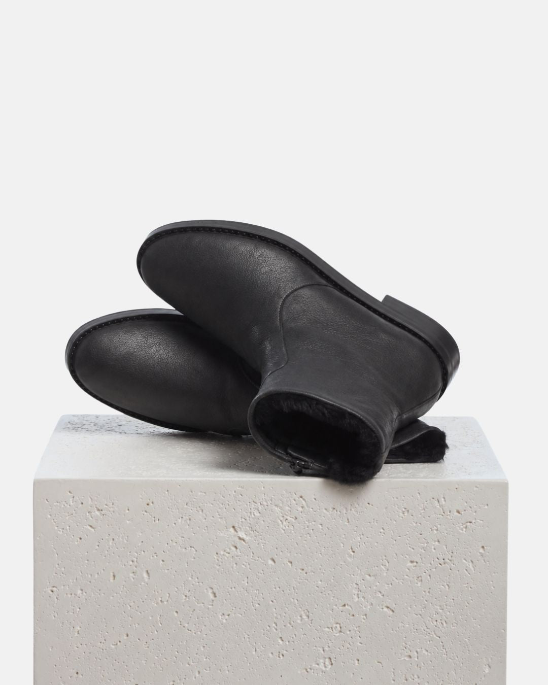 Black leather ankle boot with a low heel and a soft black shearling lining shown iso you can see the searling lining. 