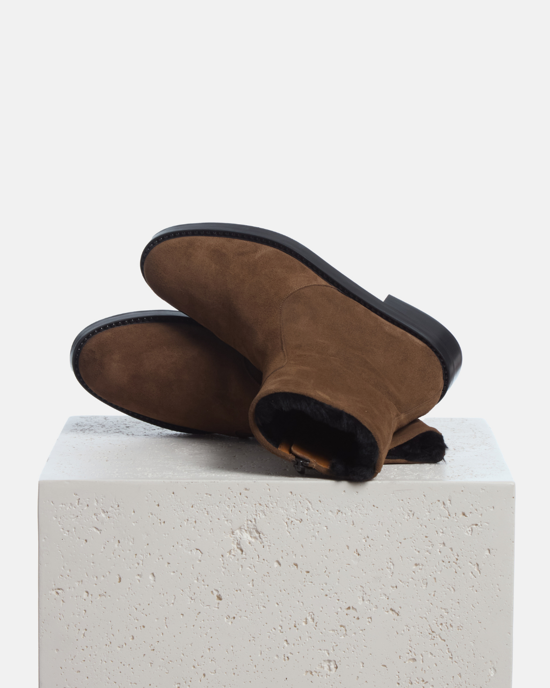 Coclico Theo Shearling Boots in Cowgirl split suede, pair of shearling lined boots resting on a stone plinth