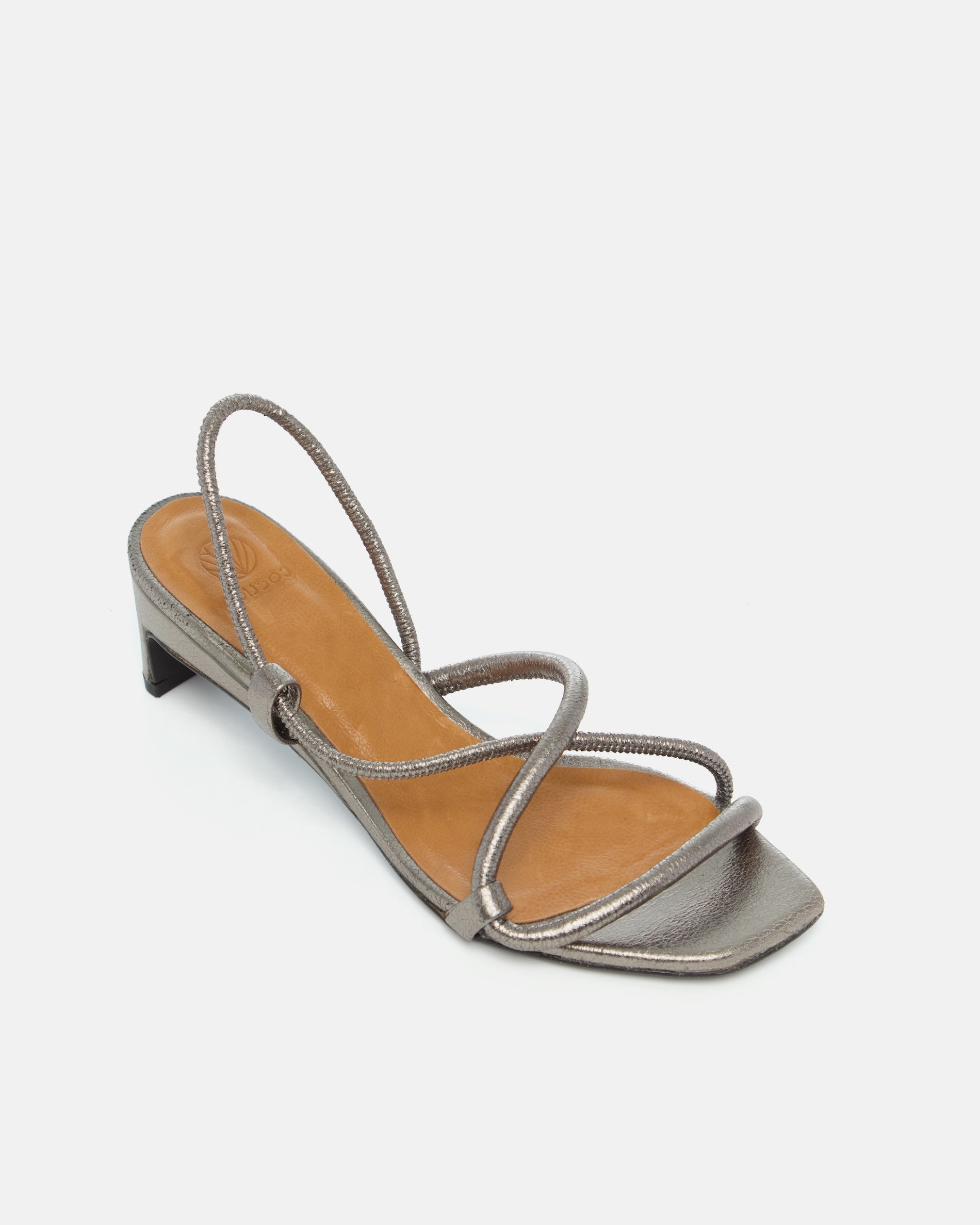 Angled view of a metallic pewter leather mid-heel sandal with slim crossover straps, an elastic slingback, and a softly contoured demi heel.