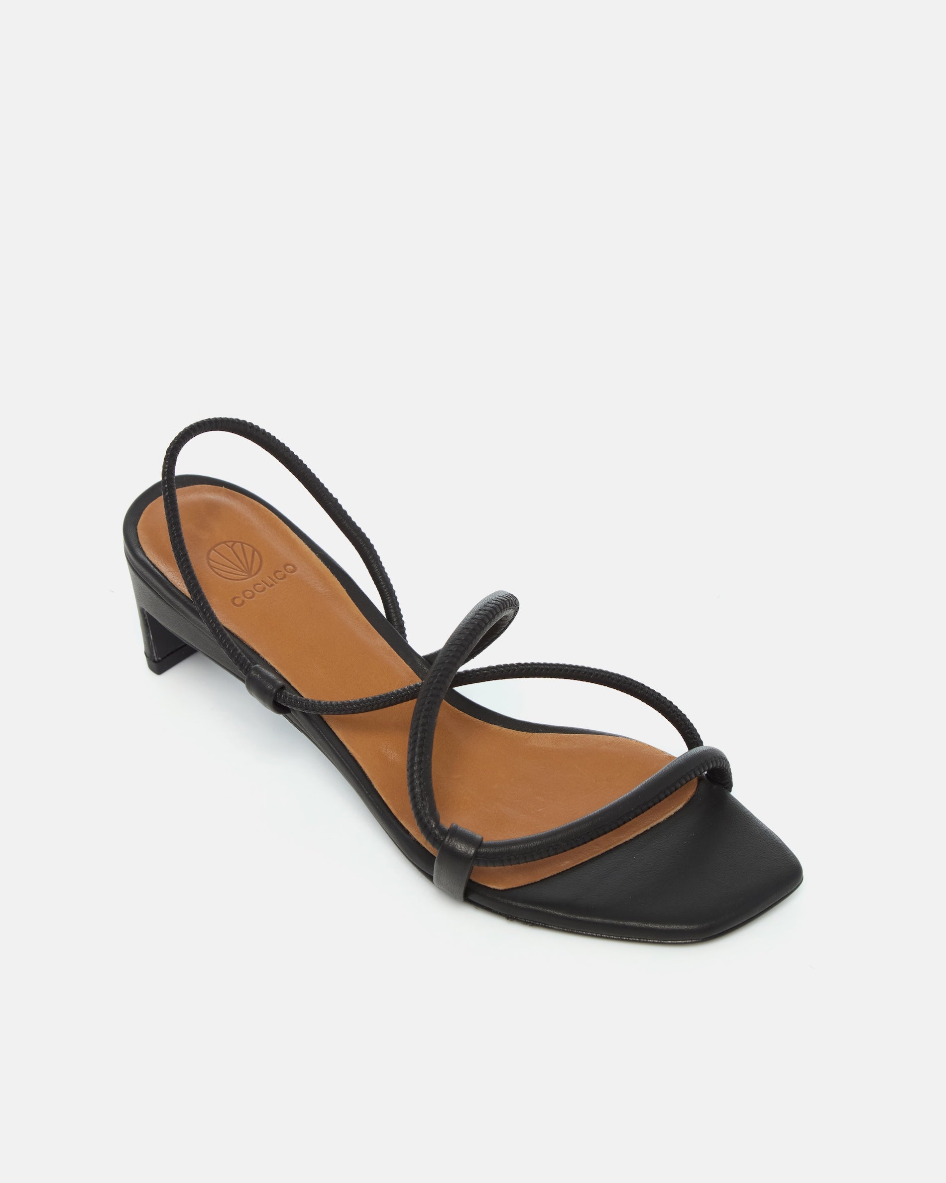Angled view of a black leather mid-heel sandal with slim straps, elasticized slingback, and a graceful demi heel