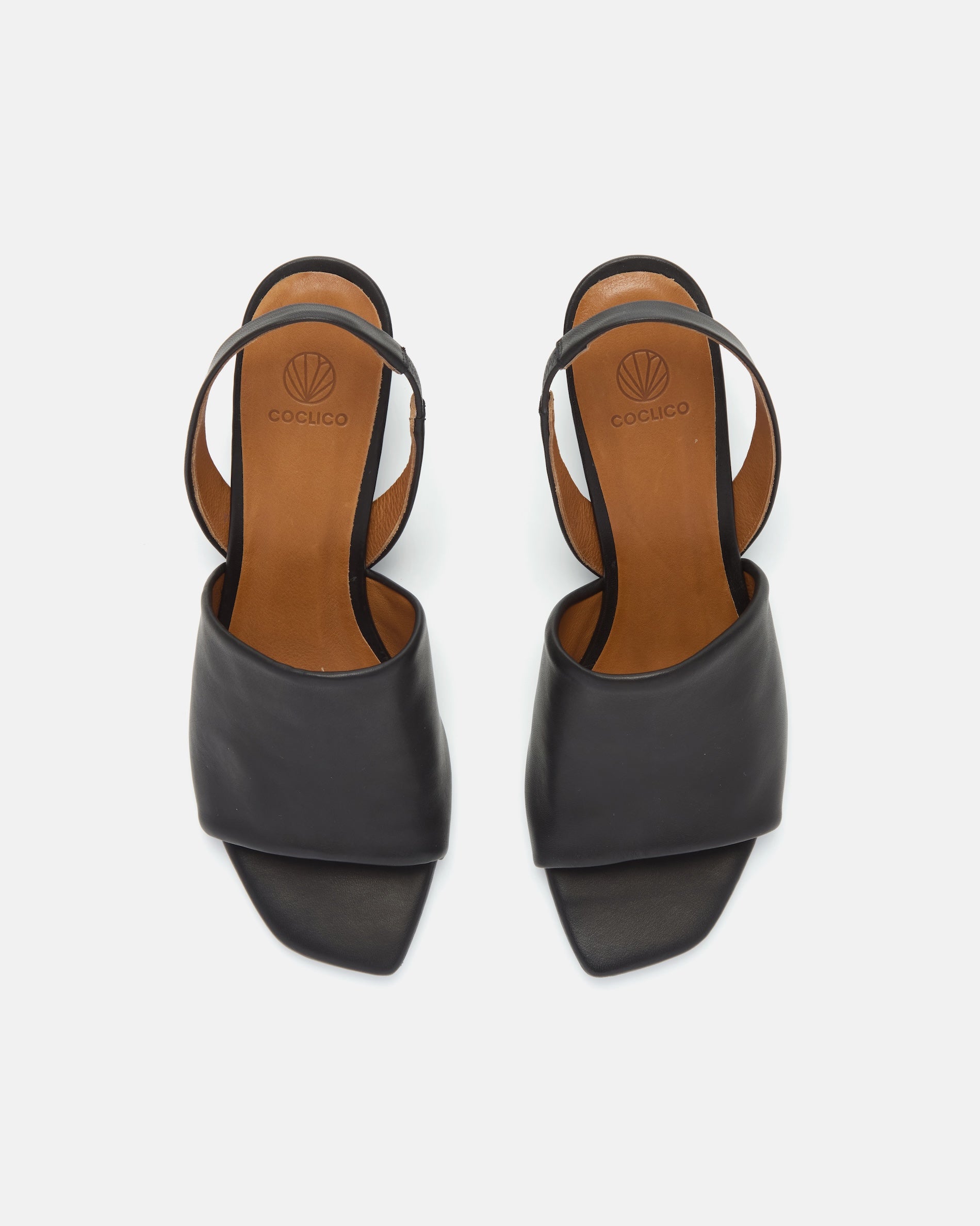 Top view of a black leather mid-heel sandal with a wide band, delicate slingback, squared toe, and sculptural block heel