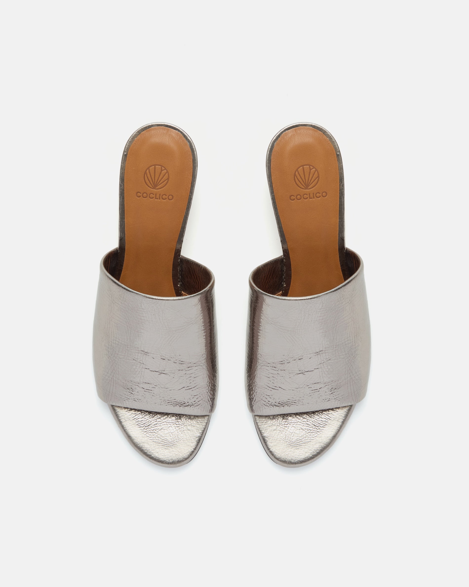 Top view of a pewter metallic slide sandal with a wide crinkled leather band and sculptural wooden demi-wedge