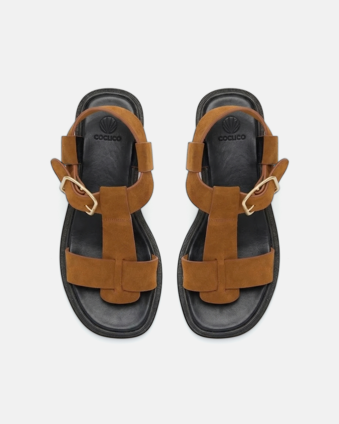 Top view of a brown suede T-strap sandal with wide straps, oversized buckle, cushioned leather footbed, and substantial sole