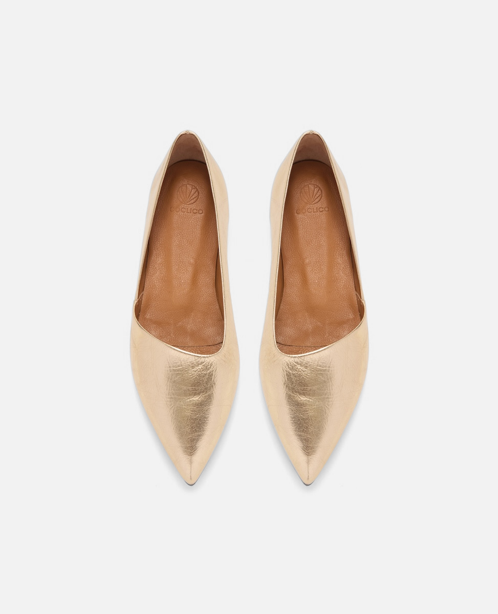 Pair of gold pointed-toe flats on a white background