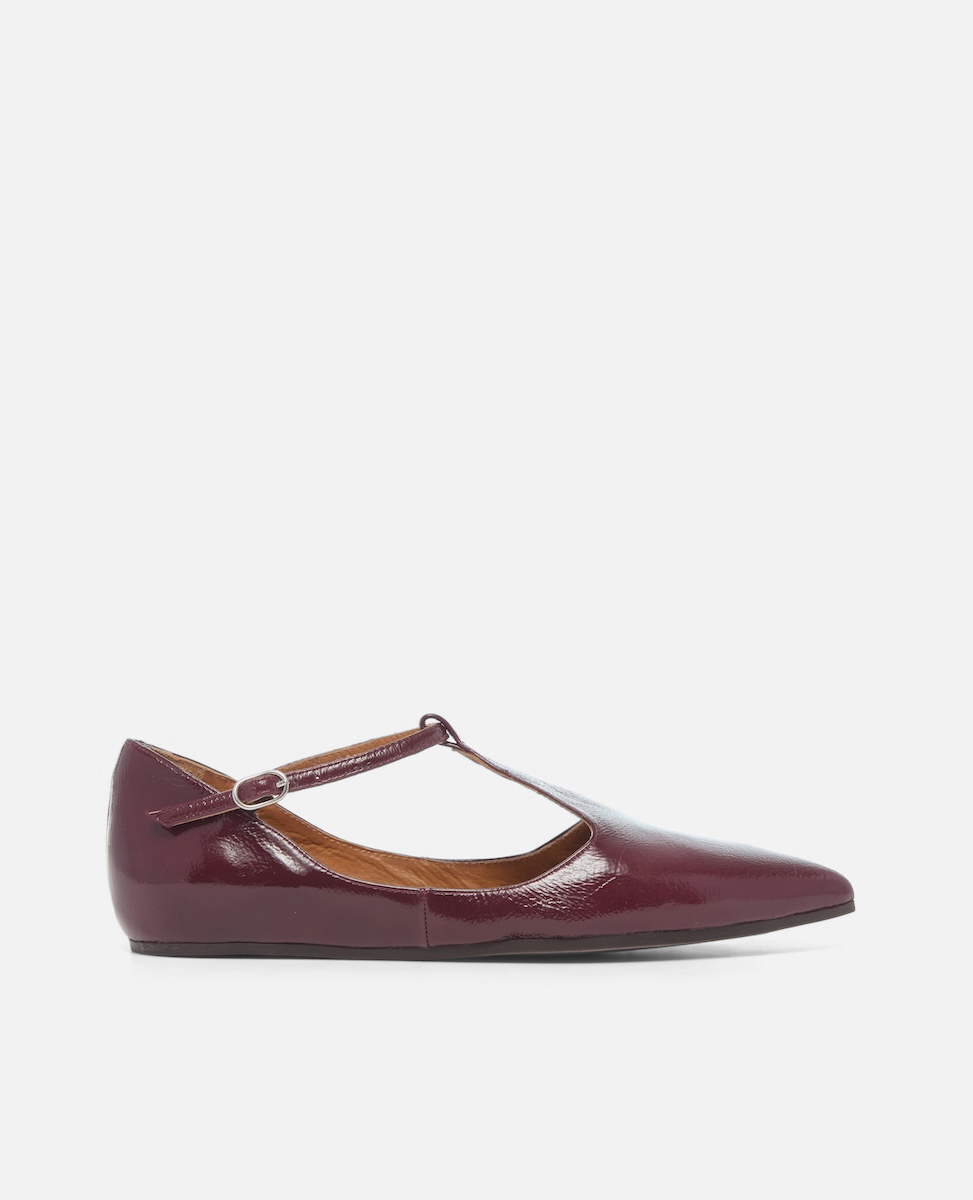 Burgundy flat shoe with a brown strap on a white background