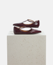 Pair of maroon shoes on a light gray pedestal against a white background 4