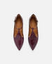 Pair of maroon pointed-toe shoes with brown soles on a white background 1