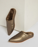 A pair of metallic bronze, pointed-toe slippers with a soft, plush brown interior lining and a smooth, slightly textured exterior, featuring a flat sole and a slip-on design. 1