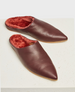 A pair of maroon, pointed-toe, slip-on slippers with a smooth leather exterior and a plush, red fur lining, featuring a flat sole and a minimalist design. 1