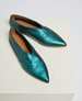 A pair of metallic teal, pointed-toe flats with a sleek, smooth texture and a unique, asymmetrical cut design, featuring a tan inner lining and a small, subtle logo embossed on the insole. 1