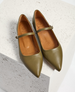 Olive green leather Mary Jane flats with pointed toes, a slim adjustable strap with a silver buckle, and a smooth, polished finish. 2