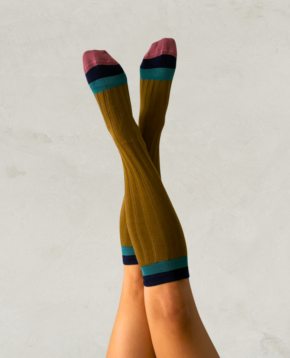 Knee-high socks with a striped pattern worn by a person on a light gray background