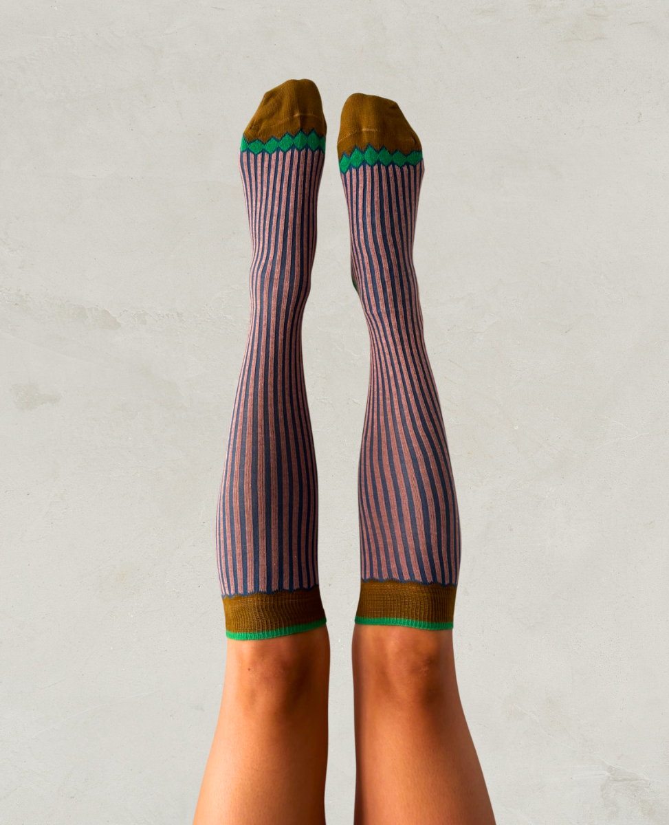 Striped knee-high socks with green and brown accents worn by a person on a light gray background