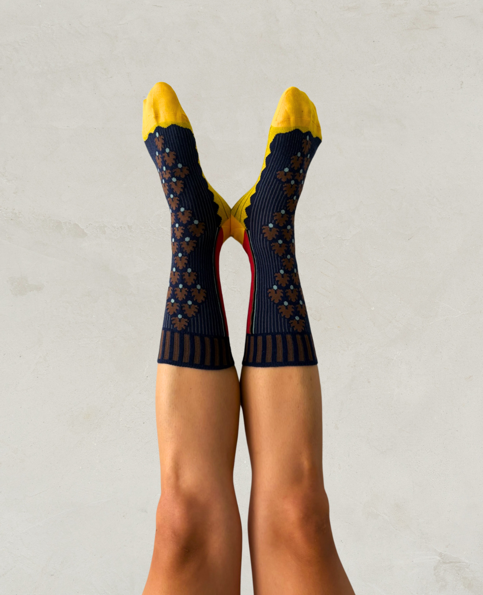 Navy patterned socks with yellow tips worn by a person on a light gray background
