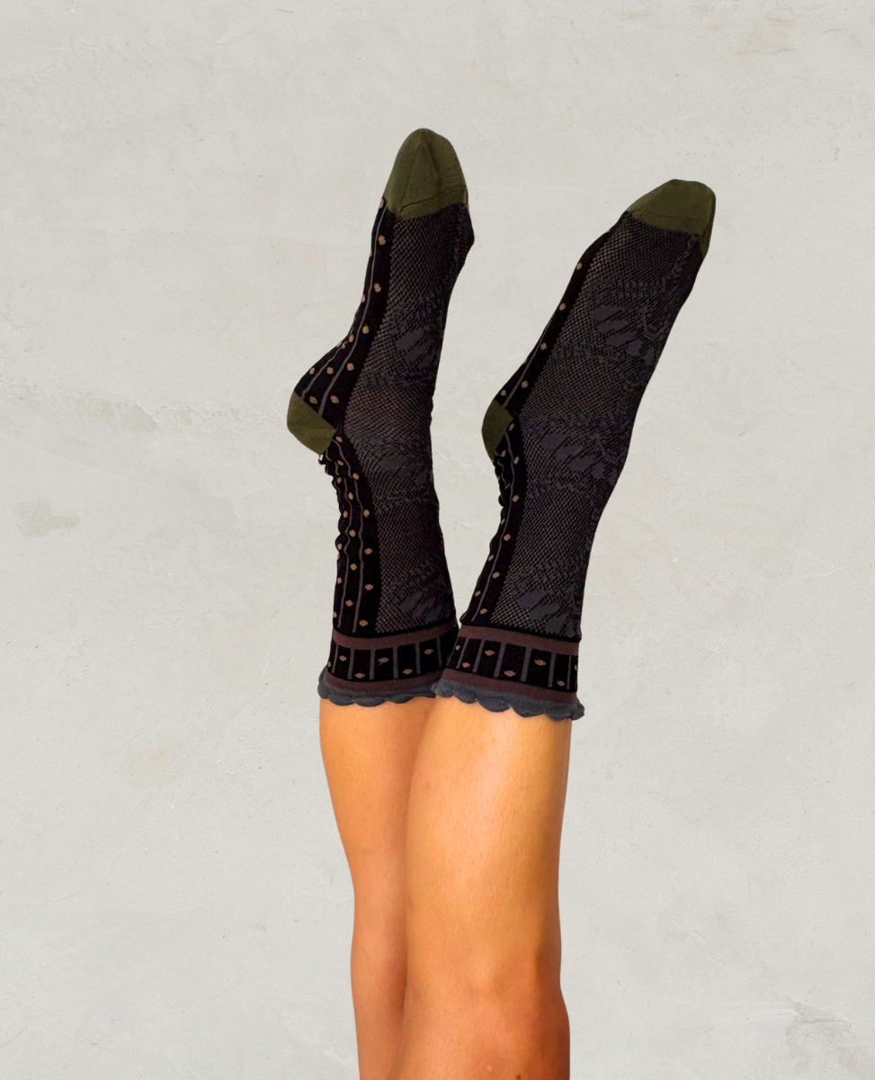 Black patterned socks worn by a person on a light gray background