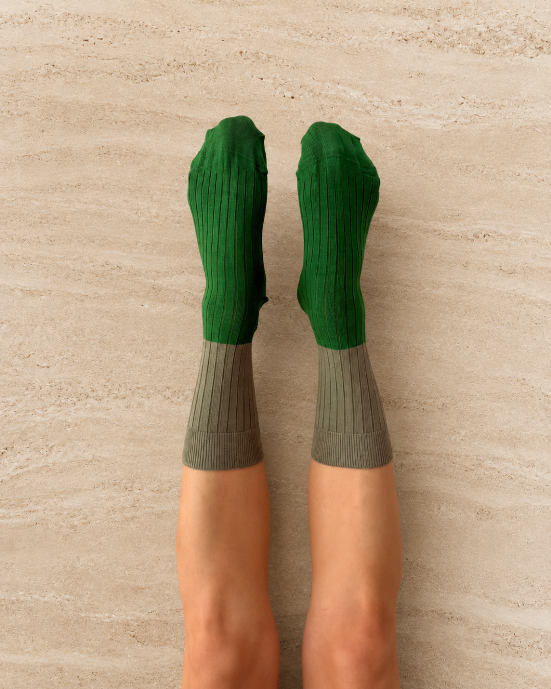 Escuyer Green and gray socks worn by a person on a stone background