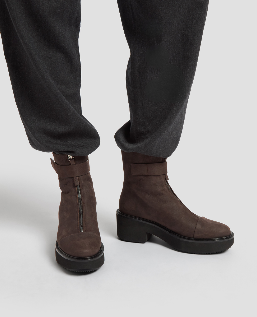 Brown ankle boots worn with black pants on a light gray background