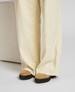 Cream-colored, wide-leg pants made of a soft, flowing fabric, paired with tan suede shoes featuring black rubber soles. 4