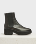 A sleek, black leather chelsea boot with a chunky heel, elastic side panels, and a smooth, polished finish, featuring a slightly rounded toe and a textured rubber sole. 1