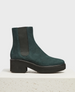 A dark blue nubuck chelsea boot with a chunky black sole, elastic side panels, and a block heel, featuring a smooth texture and a sleek, minimalist design. 1