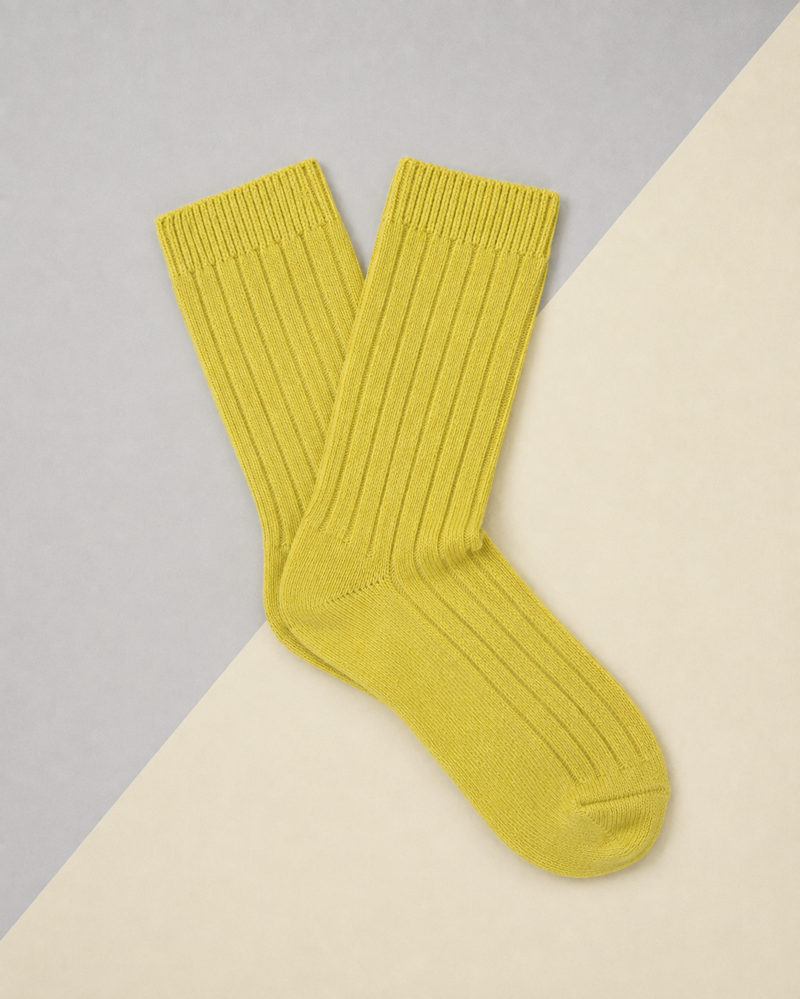 Escuyer women's cashmere crew socks in yellow on a two-tone grey and cream background