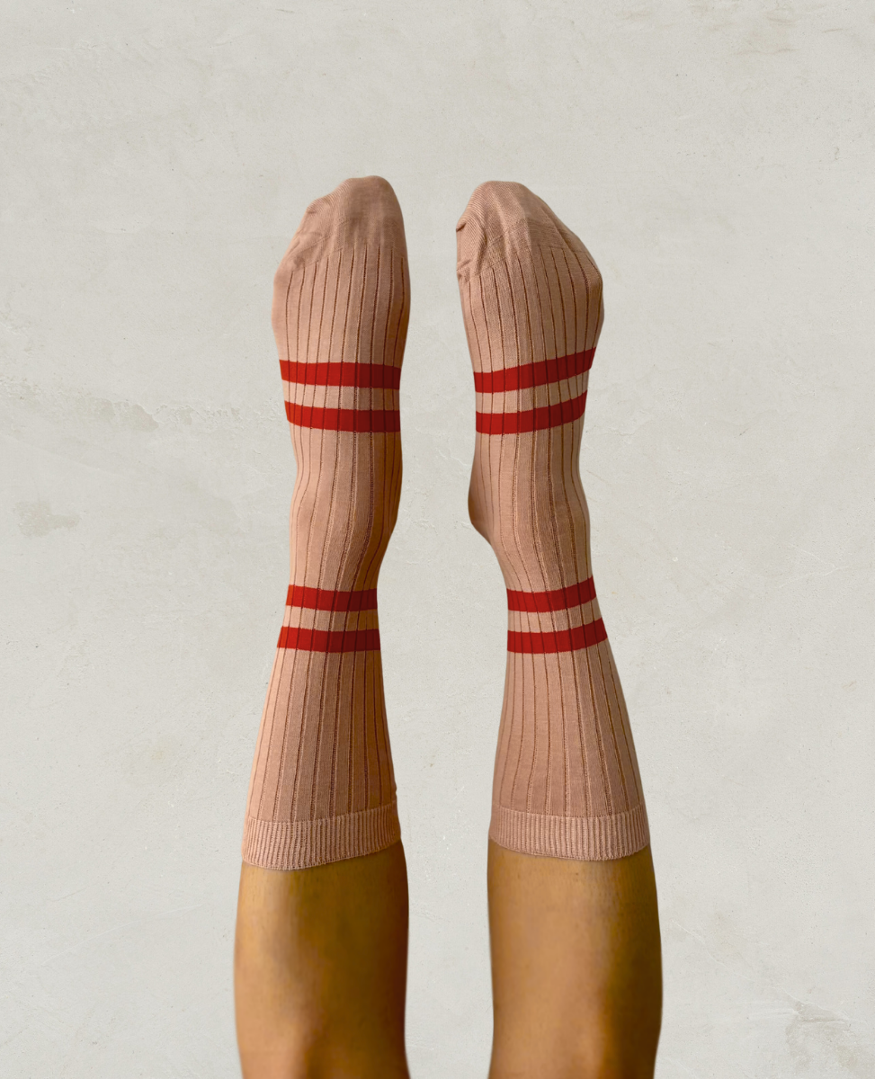 Escuyer Pink socks with red stripes worn by a person on a light gray background